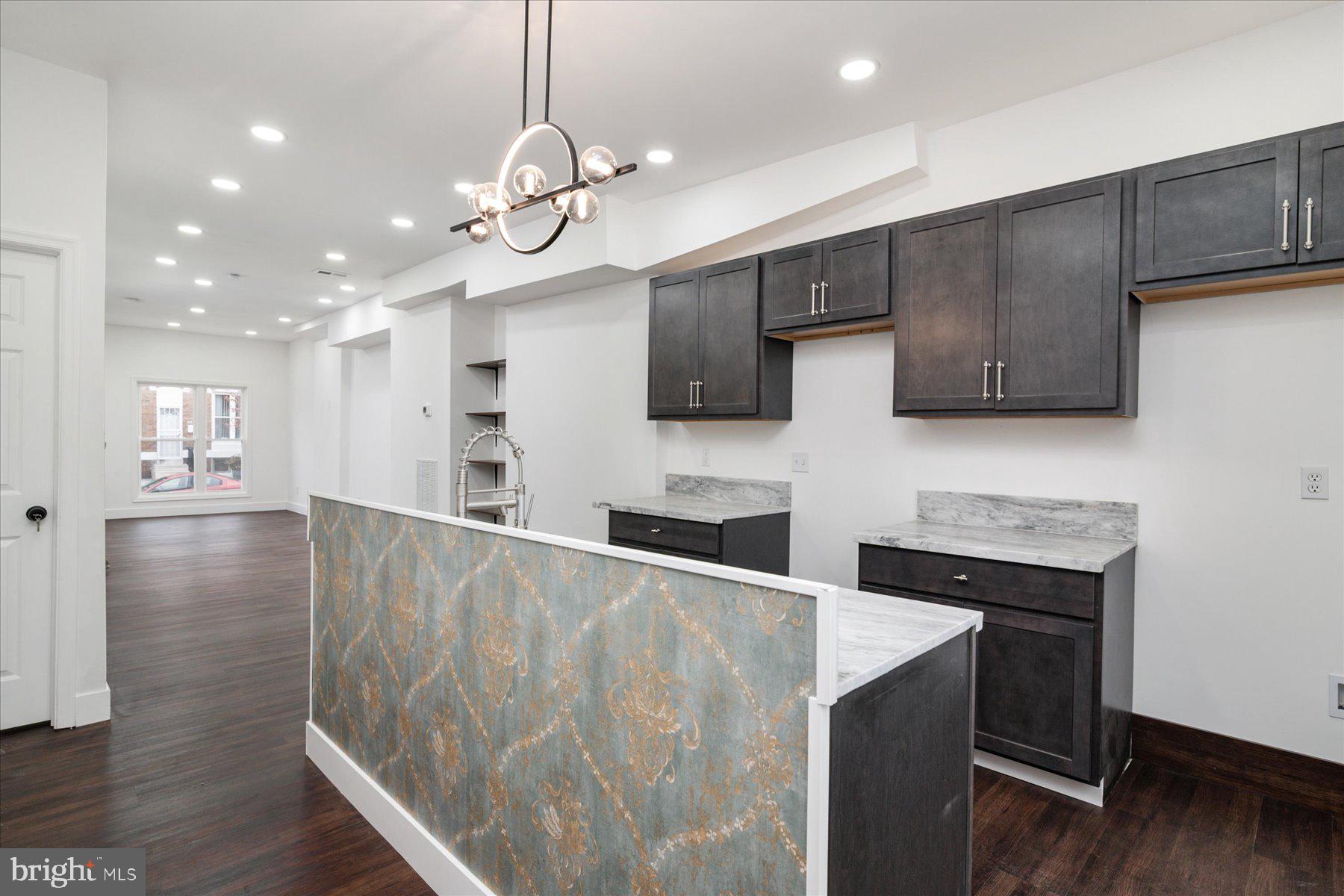 62 Gorman Avenue Baltimore, MD 21223 - Photo 11 of 24 a kitchen with stainless steel appliances granite countertop a kitchen island a stove and a wooden floors