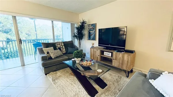 a living room with furniture a flat screen tv and a floor to ceiling window