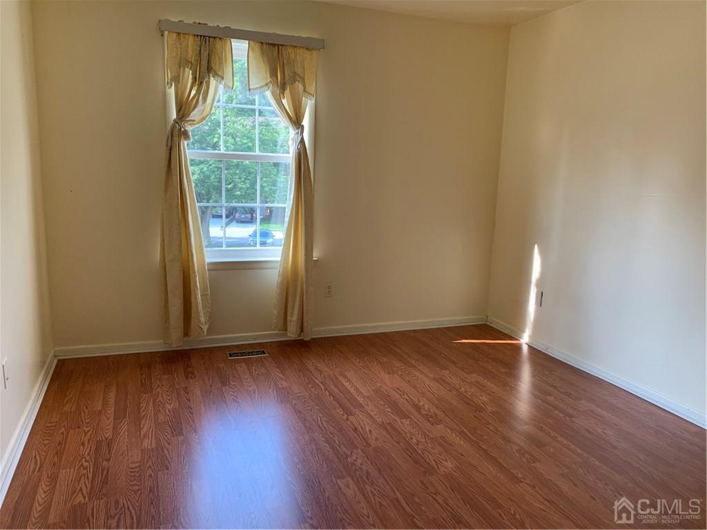 4702 Stonehedge Road Edison, NJ 08820 - Photo 19 of 24 an empty room with wooden floor and windows