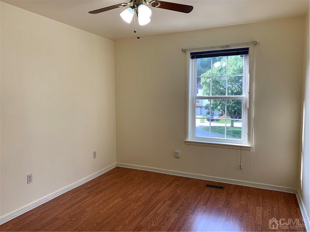 4702 Stonehedge Road Edison, NJ 08820 - Photo 20 of 24 an empty room with wooden floor and windows