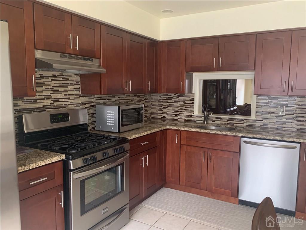 4702 Stonehedge Road Edison, NJ 08820 - Photo 2 of 24 a kitchen with granite countertop wooden cabinets and stainless steel appliances