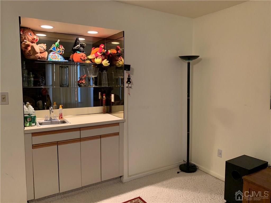 4702 Stonehedge Road Edison, NJ 08820 - Photo 22 of 24 a room with kitchen island a sink and a flat screen tv