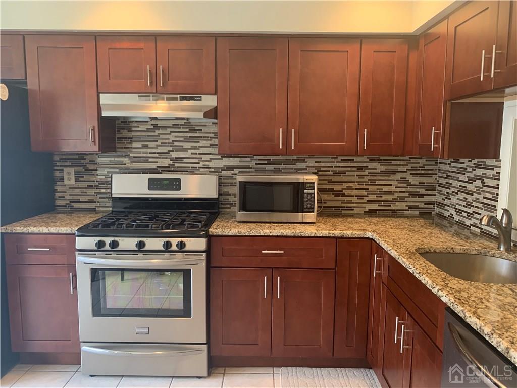 4702 Stonehedge Road Edison, NJ 08820 - Photo 3 of 24 a kitchen with granite countertop a stove top oven microwave and cabinets