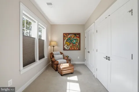 a bedroom with a bed and a couch with large windows