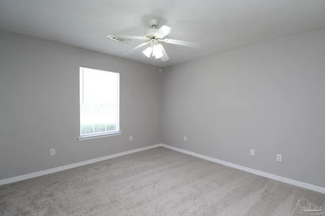 an empty room with windows and chandelier fan