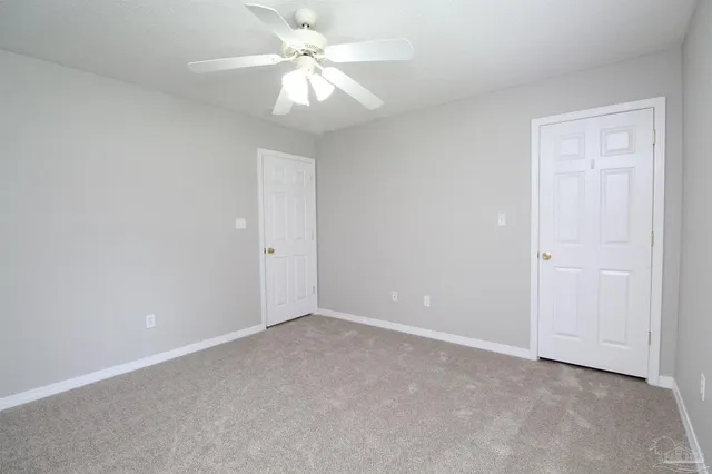 an empty room with a fan & a ceiling fan