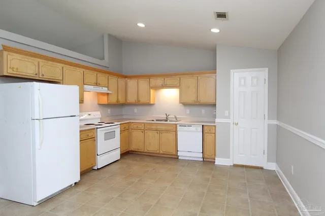 a kitchen with a refrigerator a stove top oven a sink and dishwasher with wooden floor