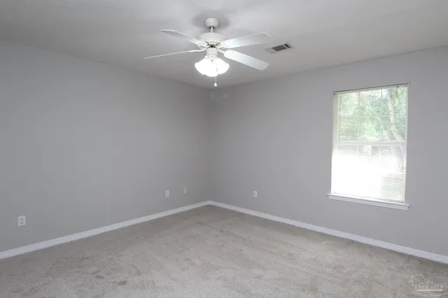 an empty room with a window and a fan