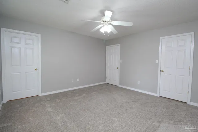 a view of an empty room with a chandelier fan