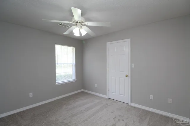 an empty room with windows and fan