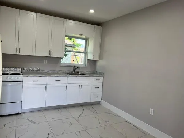 a kitchen with granite countertop white cabinets white appliances and a sink