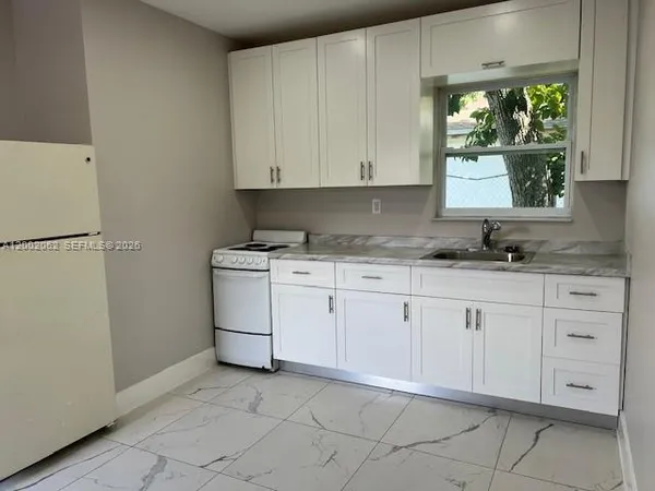 a kitchen with white cabinets and white appliances