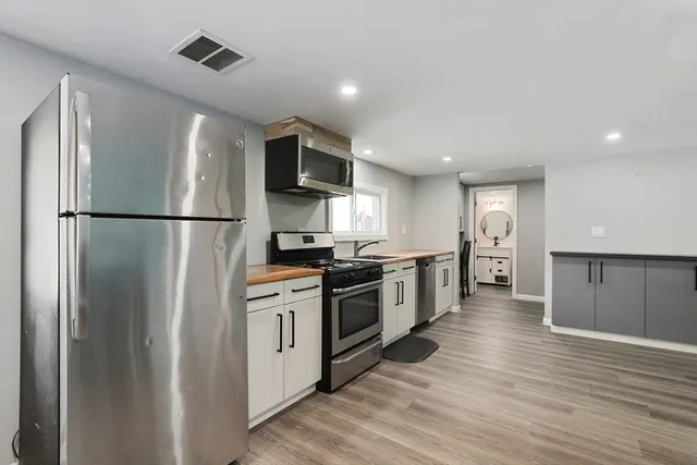 a kitchen with stainless steel appliances a refrigerator a sink and white cabinets