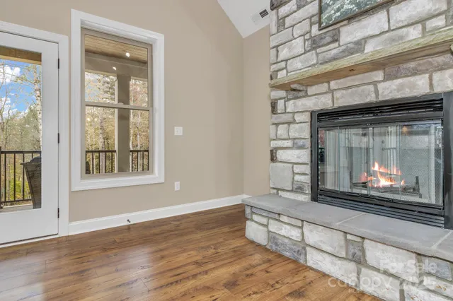 a view of an empty room with wooden floor fireplace and a window