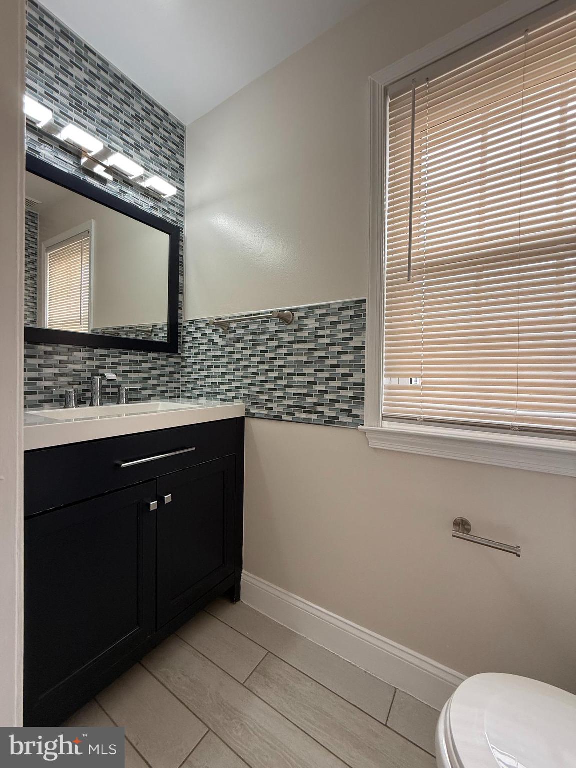 3801 Tremayne Terrace Silver Spring, MD 20906 - Photo 11 of 25 a bathroom with a toilet sink vanity and mirror