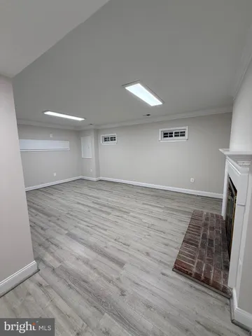 a view of an empty room with wooden floor and a fireplace