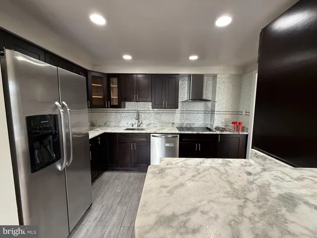 a bathroom with a sink a large mirror and a refrigerator