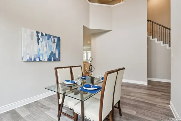 a kitchen with stainless steel appliances granite countertop a stove top oven a sink a refrigerator and white cabinets with wooden floor