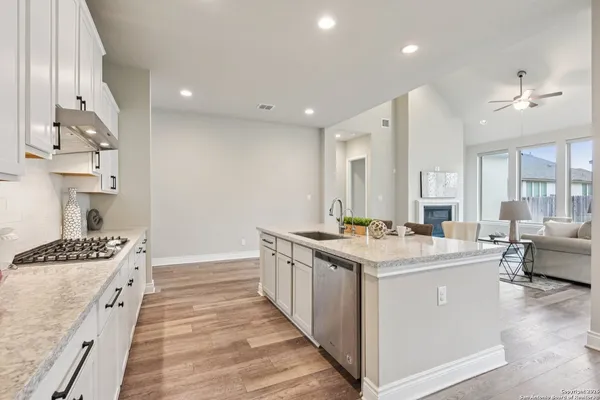 a kitchen with a sink a stove a refrigerator and white cabinets with wooden floor