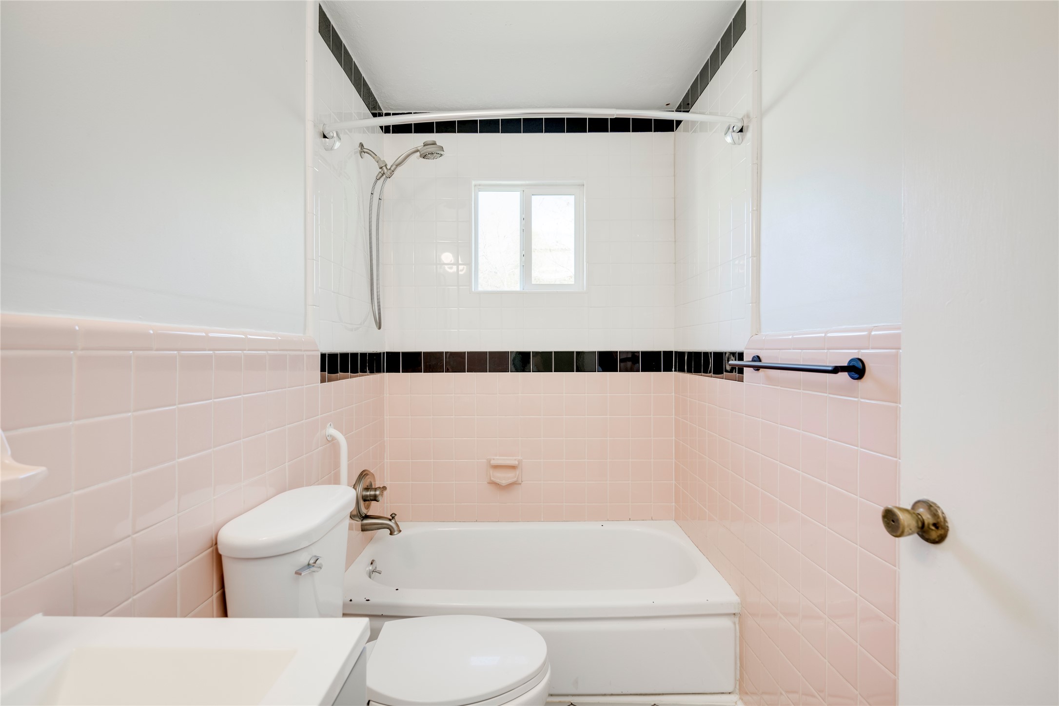 4804 Tanney Street Austin, TX 78721 - Photo 20 of 40 A neatly tiled bathroom with a classic tub and shower combination, featuring a small window for natural light.