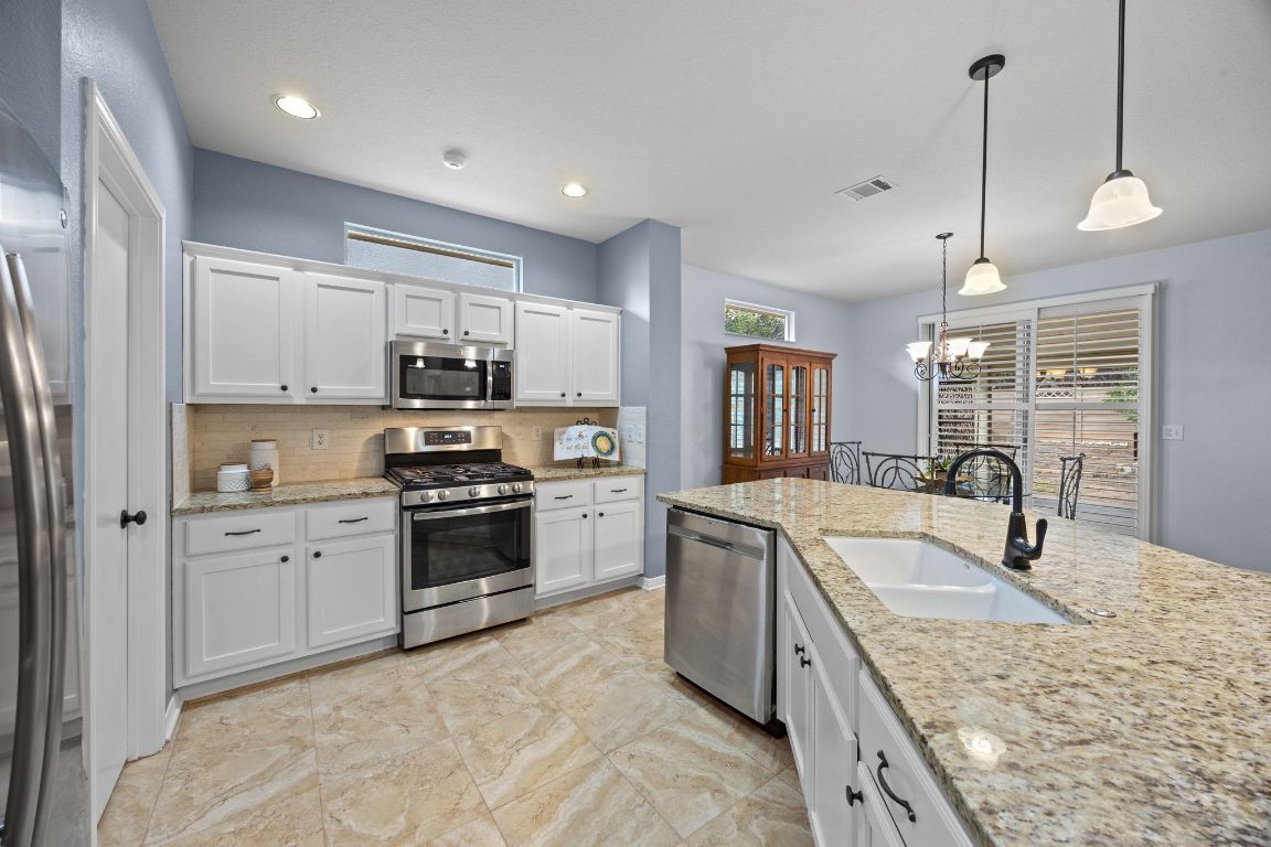 132 Trail Of The Flowers Georgetown, TX 78633 - Photo 3 of 37 a kitchen with stainless steel appliances granite countertop a sink a stove and a refrigerator
