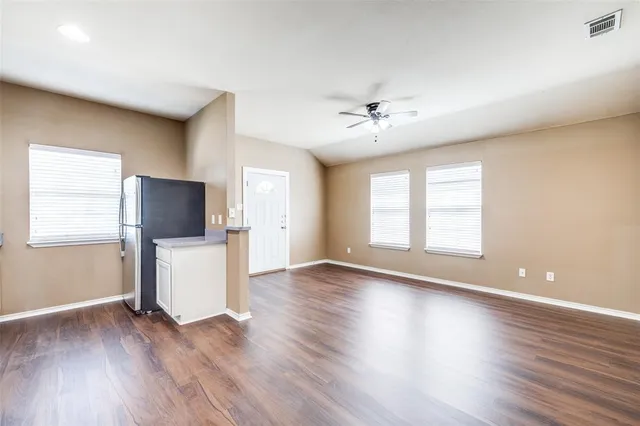 a view of an empty room with a window and wooden floor