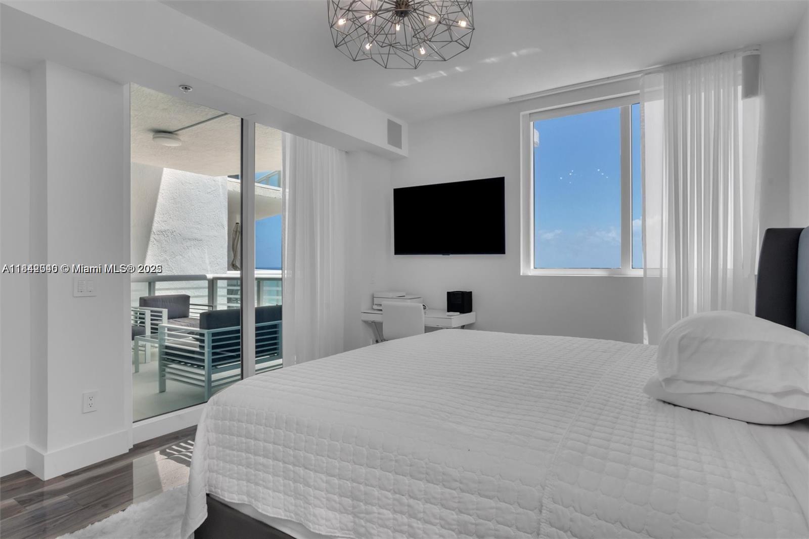 3801 Collins Avenue, Unit 1104 Miami Beach, FL 33140 - Photo 4 of 43 a bedroom with a large bed and a flat screen tv