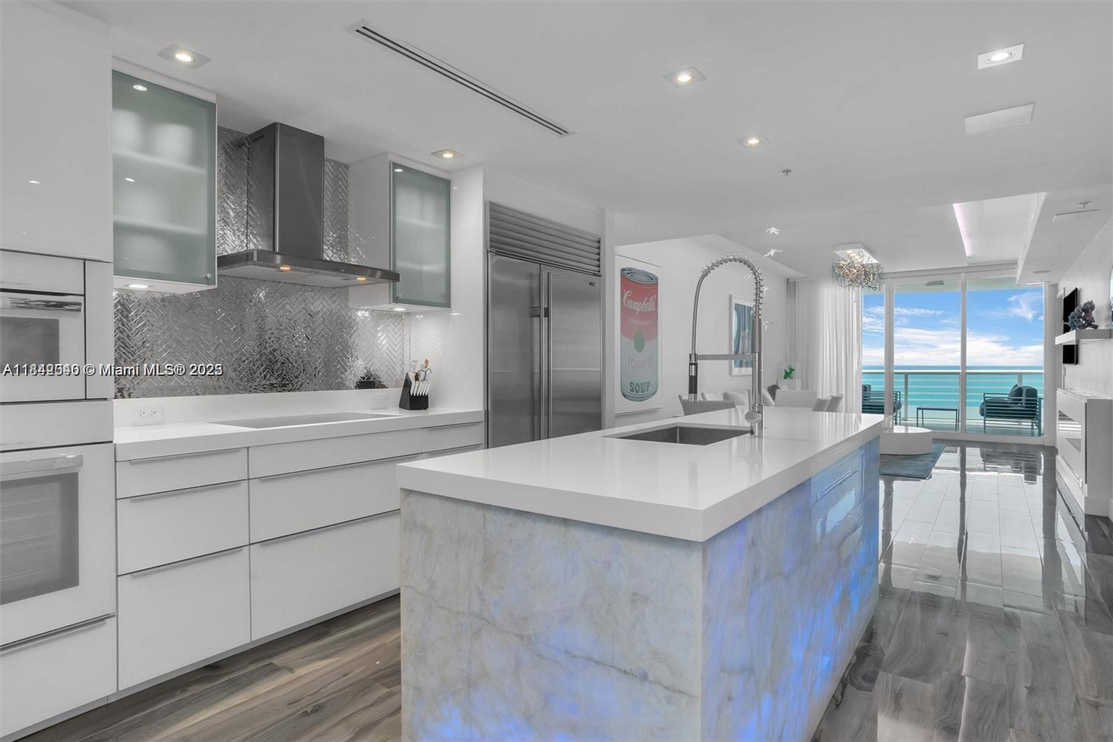 3801 Collins Avenue, Unit 1104 Miami Beach, FL 33140 - Photo 5 of 43 a kitchen with kitchen island a sink and a stove top oven