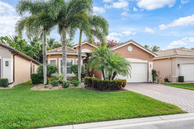a front view of a house with a yard and palm trees