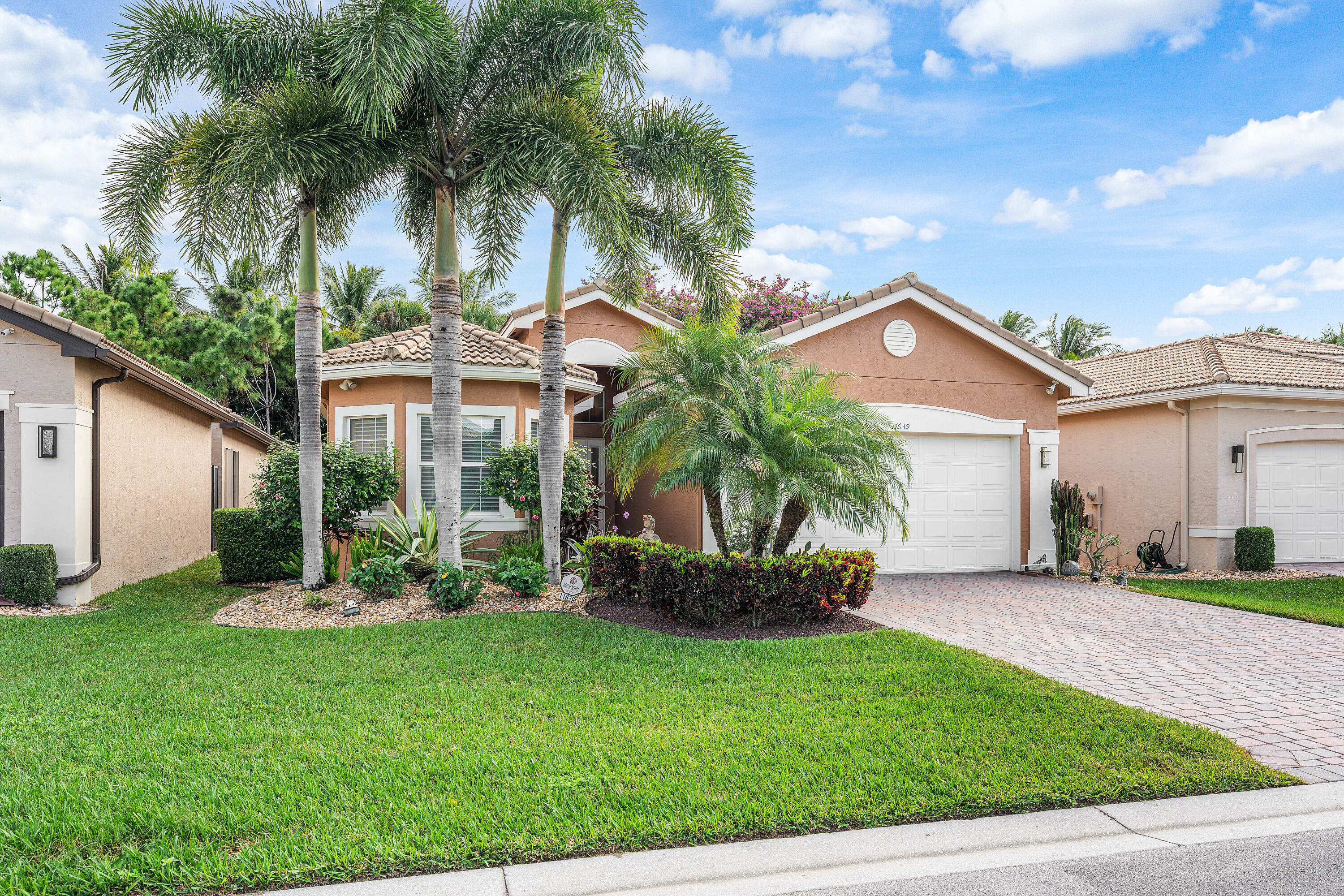 a front view of a house with a yard and palm trees