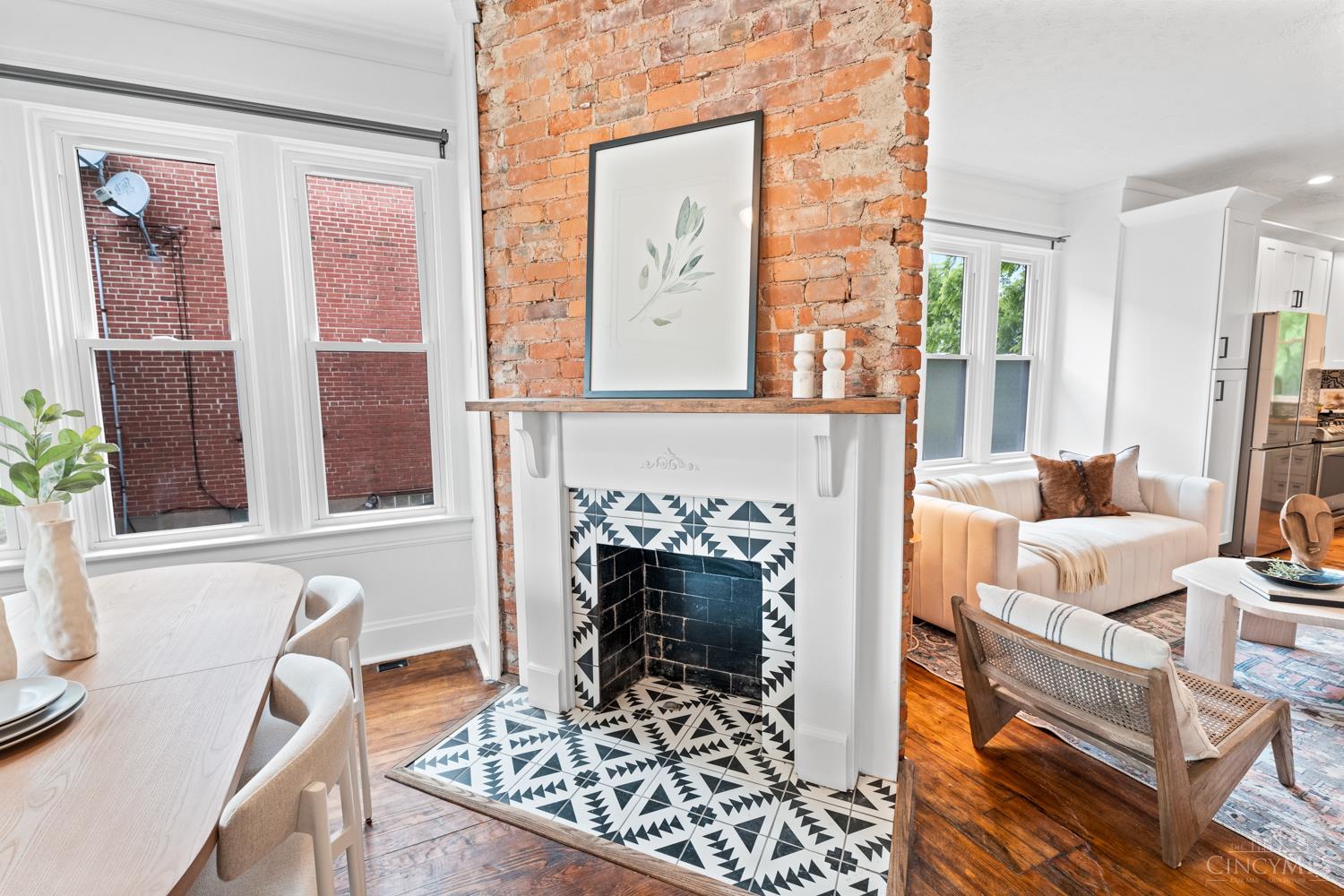 Open concept from front to back of the home with stylish finishes include exposed brick walls, brick fireplace (inoperable), original hardwood floors, butcher block countertops, an eye-catching tile backsplash, and a spa-like primary bathroom.