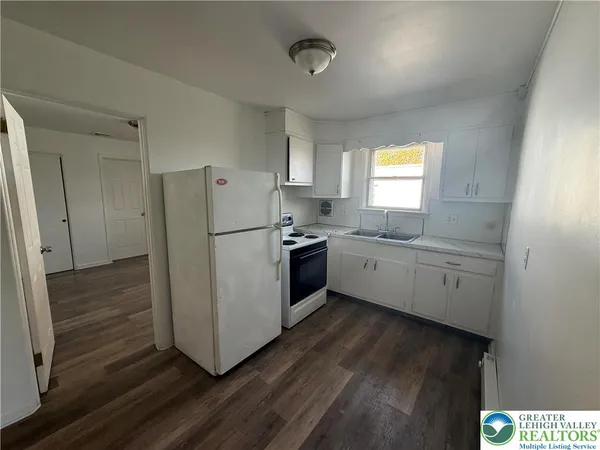 a kitchen with a refrigerator a sink and dishwasher with wooden floor