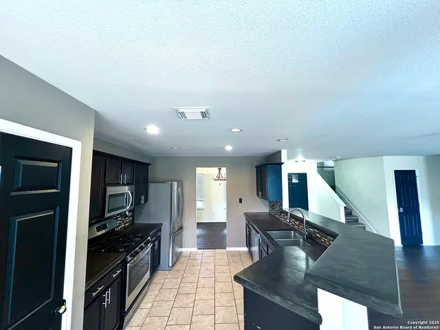 a large kitchen with stainless steel appliances kitchen island granite countertop a large counter top cabinets and a stove