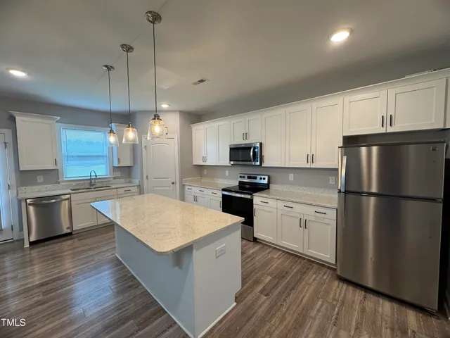 a kitchen with a refrigerator a sink and dishwasher with white cabinets