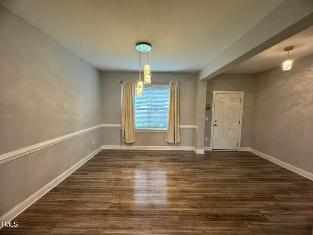 a view of an empty room with window and wooden floor