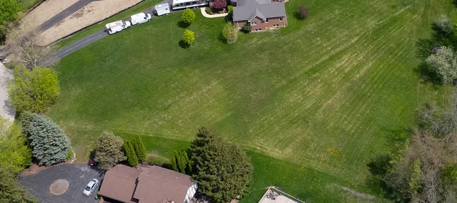 an aerial view of a residential houses with outdoor space and trees all around