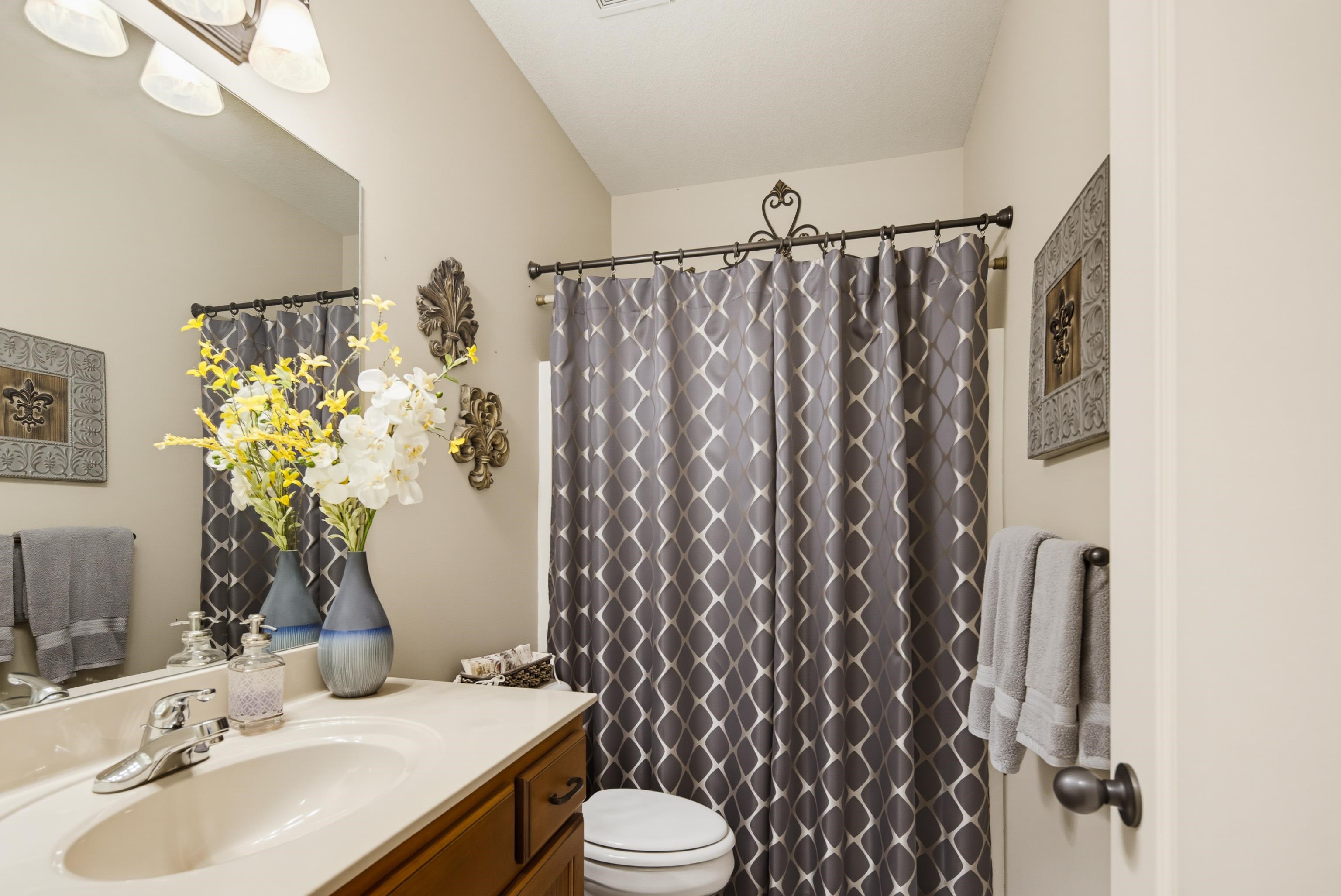 243 Hayes Road Munford, TN 38058 - Photo 17 of 25 Bathroom with a single vanity featuring a built-in sink, chrome faucet, and wood-finish cabinetry. Linen closet located behind door.