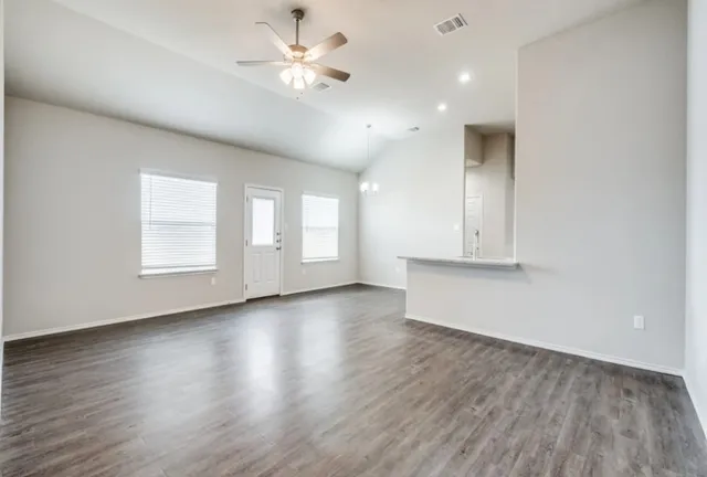 a view of an empty room with a window and wooden floor