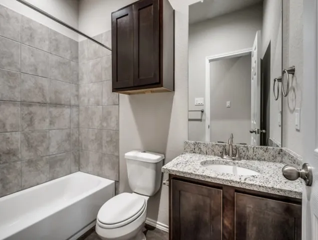 a bathroom with a granite countertop toilet a sink and a bathtub