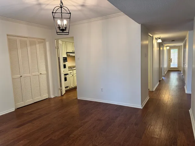 a view of a hallway with wooden floor and chandelier