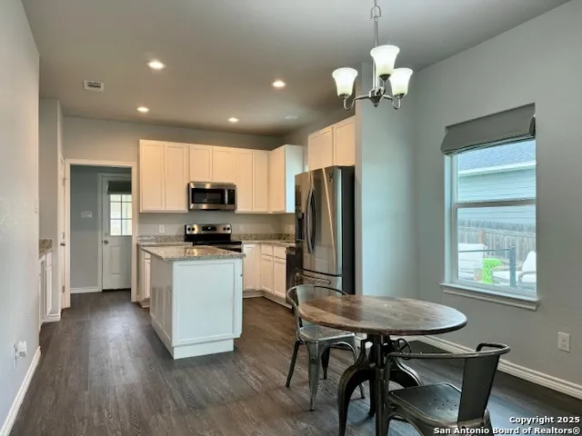 a kitchen with stainless steel appliances granite countertop a refrigerator a sink dishwasher a stove and white countertops with wooden floor