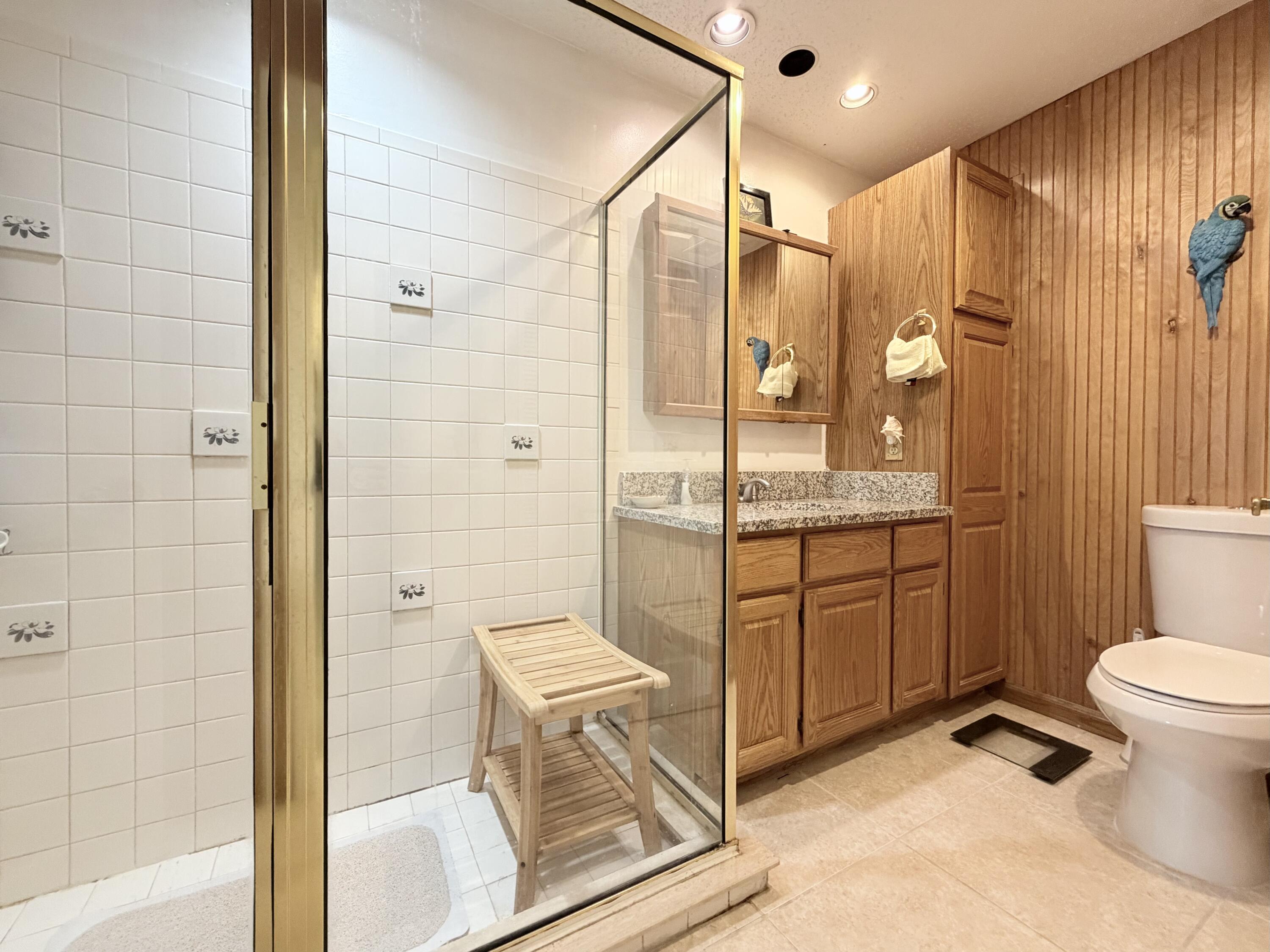 4235 North Hwy A1A, Unit 14 Hutchinson Island, FL 34949 - Photo 22 of 36 a bathroom with a granite countertop sink toilet mirror and shower