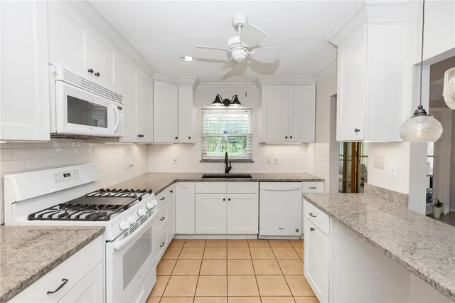 a kitchen with stainless steel appliances granite countertop a refrigerator a sink and white cabinets