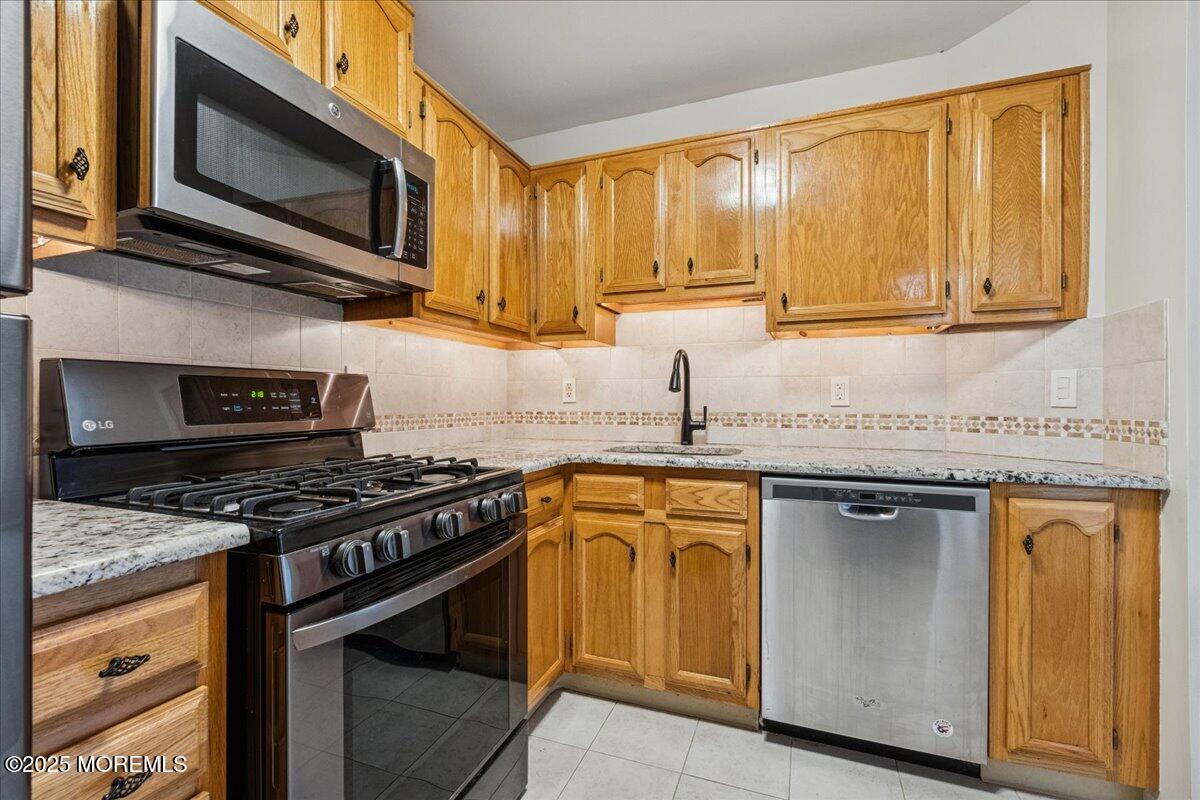 8 White Oak Court Howell, NJ 07731 - Photo 11 of 17 a kitchen with stainless steel appliances granite countertop a stove microwave sink and refrigerator