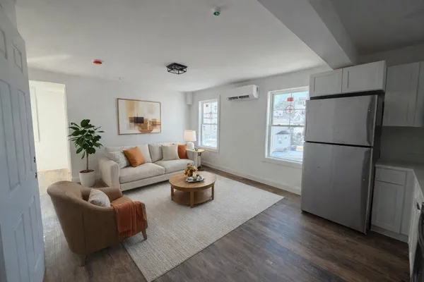 a living room with furniture wooden floor and a refrigerator