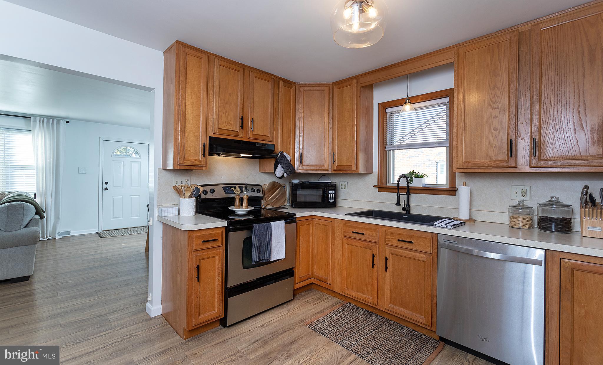 66 Runyon Road Hummelstown, PA 17036 - Photo 8 of 26 a kitchen with stainless steel appliances granite countertop a stove a sink dishwasher and microwave with wooden floor