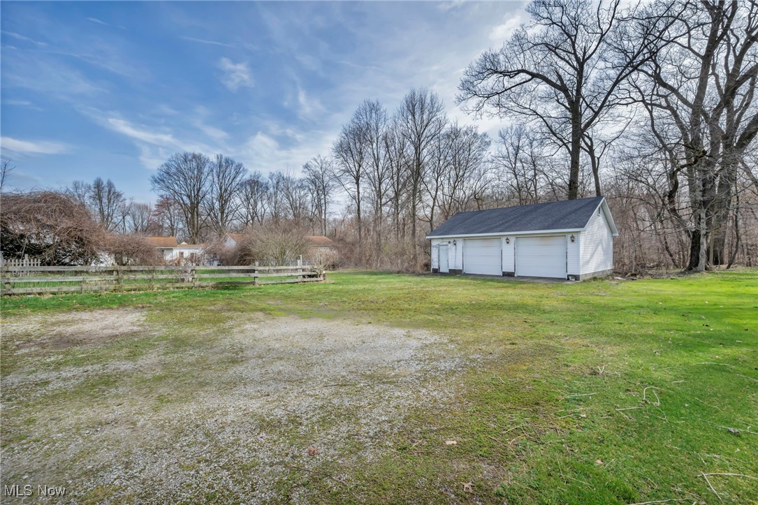 View of yard featuring fence, an outdoor structure, and a garage