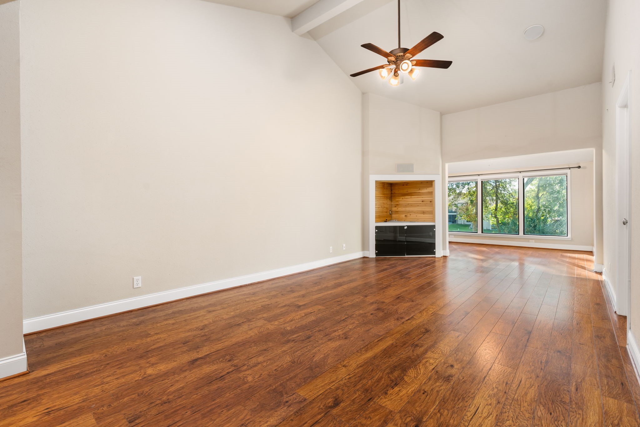 204 Lakeview Terrace, Unit G Conroe, TX 77356 - Photo 9 of 26 an empty room with wooden floor chandelier fan and windows