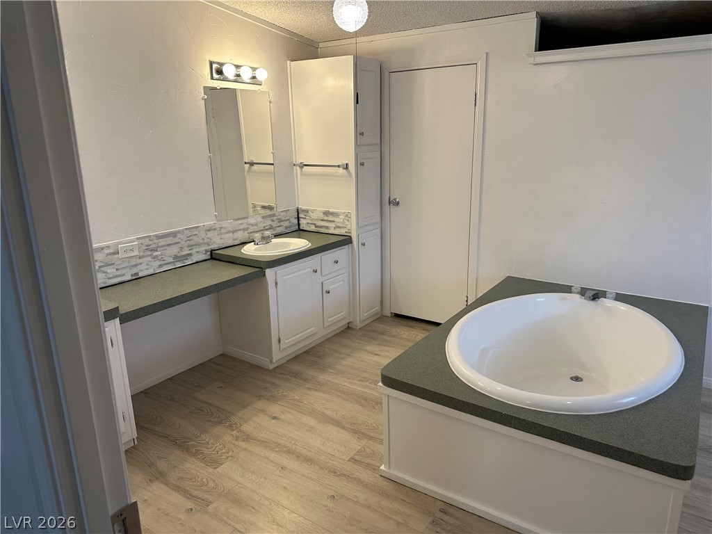 3270 West Simkins Road Pahrump, NV 89060 - Photo 17 of 36 A spacious bathroom features wood-look flooring and a deep circular soaking tub.
