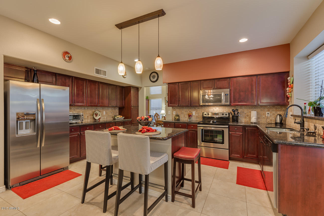 11255 West Piccadilly Road Avondale, AZ 85392 - Photo 16 of 29 a kitchen with stainless steel appliances granite countertop a sink a stove a refrigerator cabinets and chairs